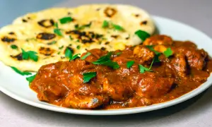 En krämig chicken tikka masala med naanbröd, garnerad med färsk persilja.
