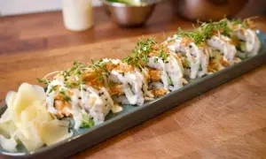 En rad läckra sushirullar med lax, gurka och krämig sås, toppade med krispiga lökar och groddar. Perfekt för ett enkelt sushi recept.