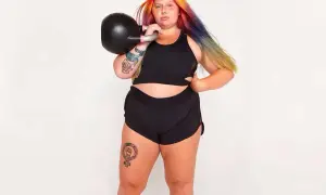 Kvinna med färgglatt hår tränar med kettlebell. Frågan "hur får man smalare lår" kan besvaras med styrketräning som denna.