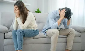 Ett par sitter på en soffa, båda med händerna för ansiktet. Mannen verkar förtvivlad, kanske på grund av att han är notorisk otrogen.