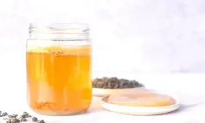 En burk med fermenterad dryck, teblad och en SCOBY. Perfekt för ditt kombucha recept.