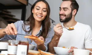 Ett leende par äter frukost tillsammans, en stund att hitta tillbaka till varandra i vardagen.