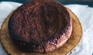 En gudomlig glutenfri chokladkaka, pudrad med kakao, serverad på en träskiva.