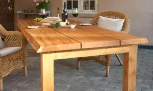 Ett rustikt diy soffbord i trä, dukat för en mysig fika utomhus med vin, bröd och ost. Korgstolar ramar in.