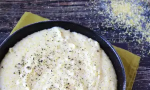 Krämig polenta i en gjutjärnspanna, strödd med peppar. Perfekt för ett enkelt polenta recept.