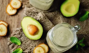 Grön smoothie med avokado och banan, perfekt som mat med lite kalorier. Serveras i glasburkar med myntablad.