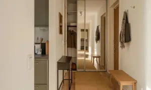 En ljus och inreda hall med en spegelgarderob, en smal konsol, en träbänk och en matta.