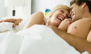 Ett par skrattar i sängen. Klimakteriet kan påverka sexlusten, men medicin kan hjälpa.