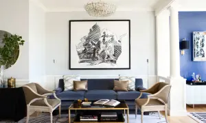Elegant vardagsrum med en djupblå soffa som blickfång. En stor svartvit tavla och en kristallkrona ger inspiration.