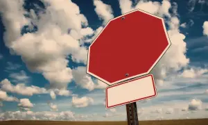 Tomt stoppskylt i ett öppet landskap med molnig himmel. Känns som att man måste tacka nej till inbjudan.