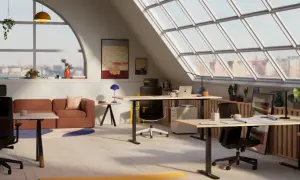 Ett ljust och modernt kontor med flera skrivbord mitt i rummet, soffa och stora fönster med utsikt över en stad.