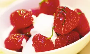 En skål med saftiga, limemarinerade jordgubbar och fluffig grädde. En härlig sommardessert.