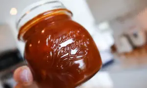 En hand håller ett glas med en härlig rabarber chutney.