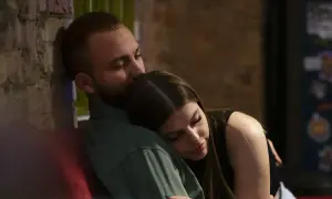 En man kysser en kvinna på pannan. De sitter nära varandra, en bild av trygghet och kärlek, som visar grundstenar i en relation.