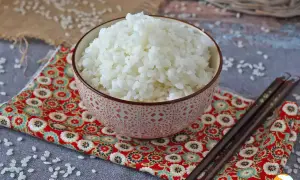 Perfekt sushiris i en vacker skål, redo för ditt sushirecept. Ätpinnar ligger bredvid.