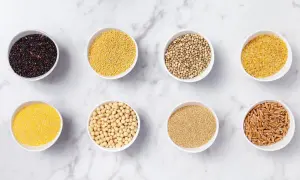Åtta skålar med olika spannmål och frön, som quinoa, hirs och bovete. Perfekt för billig mat och hälsosamma måltider.
