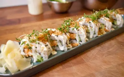 En rad läckra sushirullar med lax, gurka och krämig sås, toppade med krispiga lökar och groddar. Perfekt för ett enkelt sushi recept.