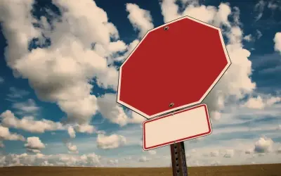 Tomt stoppskylt i ett öppet landskap med molnig himmel. Känns som att man måste tacka nej till inbjudan.