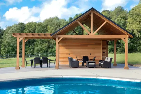 En stor träpergola med tak och sittgrupper vid en blå pool. Kanske är det här man behöver pergola bygglov för att skapa en perfekt uteplats.