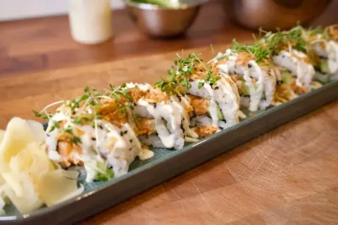 En rad läckra sushirullar med lax, gurka och krämig sås, toppade med krispiga lökar och groddar. Perfekt för ett enkelt sushi recept.