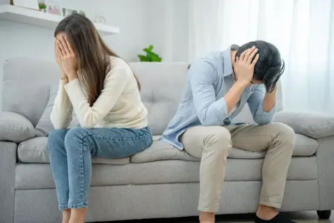Ett par sitter på en soffa, båda med händerna för ansiktet. Mannen verkar förtvivlad, kanske på grund av att han är notorisk otrogen.