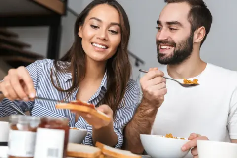 Ett leende par äter frukost tillsammans, en stund att hitta tillbaka till varandra i vardagen.