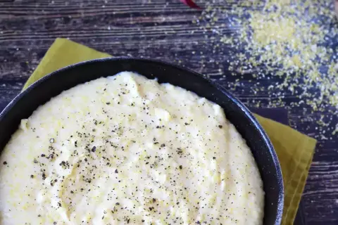 Krämig polenta i en gjutjärnspanna, strödd med peppar. Perfekt för ett enkelt polenta recept.