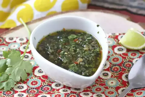 En skål med färsk chimichurri, perfekt för ditt nästa grillrecept. Serveras med lime och koriander.