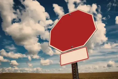 Tomt stoppskylt i ett öppet landskap med molnig himmel. Känns som att man måste tacka nej till inbjudan.