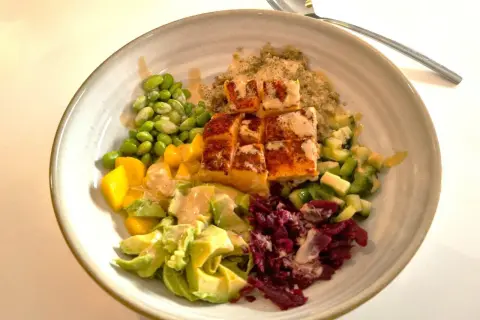 En färgglad bowl med lax, quinoa, edamame, mango, avokado och rödbetor. Perfekt nyttig snabbmat för en hälsosam lunch eller middag.
