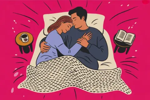 Ett par kramas i sängen. En bok och en kaffekopp står på sängbordet. Kärlek och intimitet, även under mens.