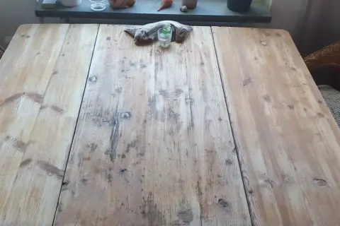 Ett slitet furubord med en bit drivved och ett glas med en växt. Kanske dags att slipa furubordet för att ge det nytt liv.