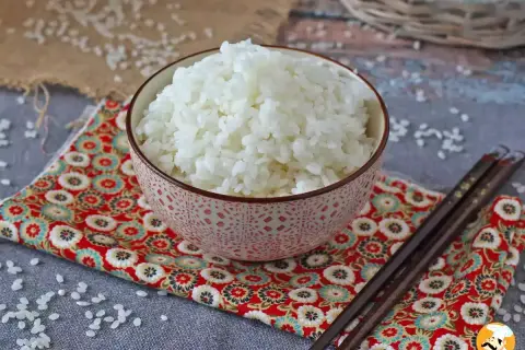 Perfekt sushiris i en vacker skål, redo för ditt sushirecept. Ätpinnar ligger bredvid.