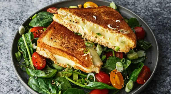 En gyllene, smältande tuna melt serveras på en bädd av färsk spenat, körsbärstomater och gurka.