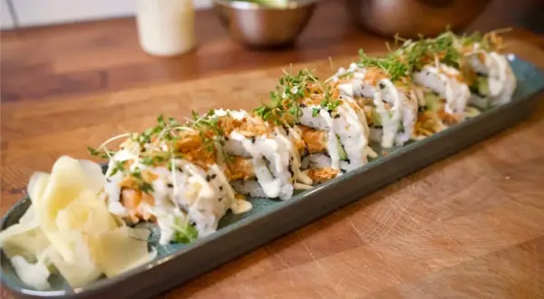 En rad läckra sushirullar med lax, gurka och krämig sås, toppade med krispiga lökar och groddar. Perfekt för ett enkelt sushi recept.