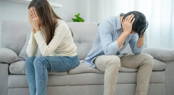 Ett par sitter på en soffa, båda med händerna för ansiktet. Mannen verkar förtvivlad, kanske på grund av att han är notorisk otrogen.