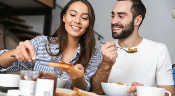 Ett leende par äter frukost tillsammans, en stund att hitta tillbaka till varandra i vardagen.