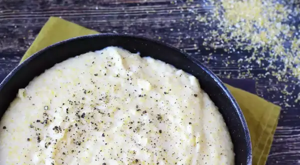 Krämig polenta i en gjutjärnspanna, strödd med peppar. Perfekt för ett enkelt polenta recept.