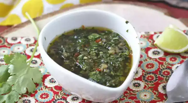 En skål med färsk chimichurri, perfekt för ditt nästa grillrecept. Serveras med lime och koriander.