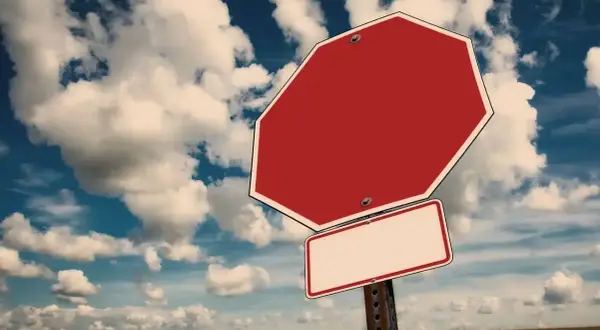 Tomt stoppskylt i ett öppet landskap med molnig himmel. Känns som att man måste tacka nej till inbjudan.
