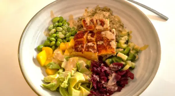 En färgglad bowl med lax, quinoa, edamame, mango, avokado och rödbetor. Perfekt nyttig snabbmat för en hälsosam lunch eller middag.