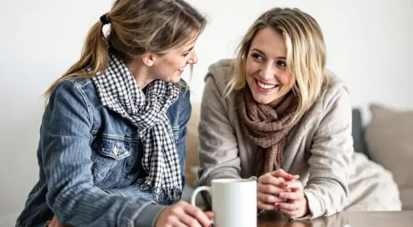 Två kvinnor ler mot varandra över en kaffemugg. De ser ut att vara vänner som pratar, inte alls som otacksamma vuxna barn.