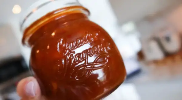 En hand håller ett glas med en härlig rabarber chutney.