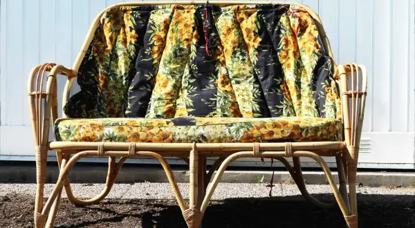 En soffa i konstrotting med blommiga dynor. Perfekt för att måla och skapa en unik möbel.