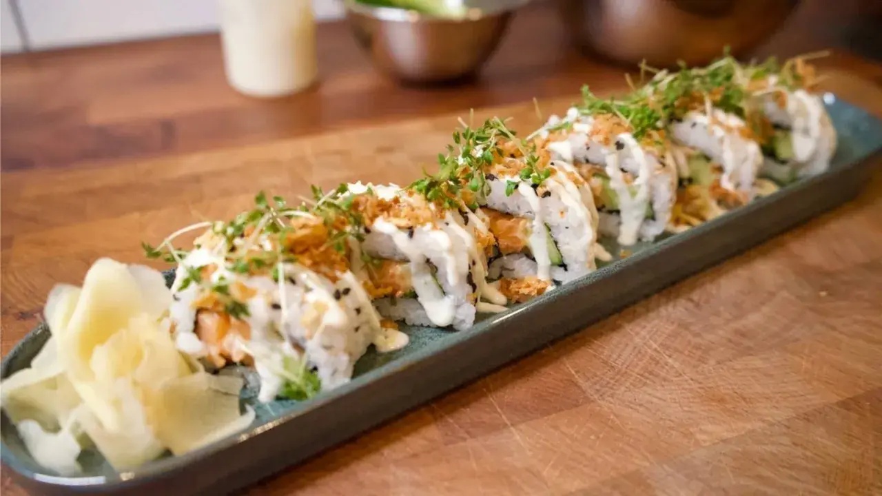 En rad läckra sushirullar med lax, gurka och krämig sås, toppade med krispiga lökar och groddar. Perfekt för ett enkelt sushi recept.