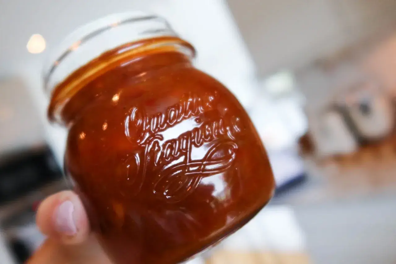 En hand håller ett glas med en härlig rabarber chutney.