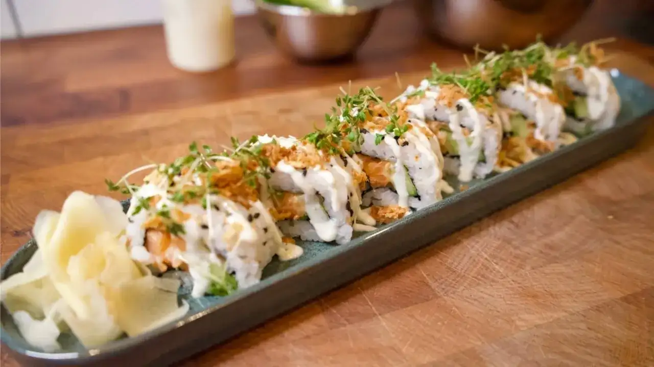 En rad läckra sushirullar med lax, gurka och krämig sås, toppade med krispiga lökar och groddar. Perfekt för ett enkelt sushi recept.