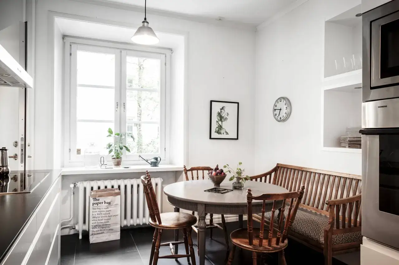 Mysig köksvrå med runt matbord, träbänk och stolar. Perfekt för runt matbord inspiration.