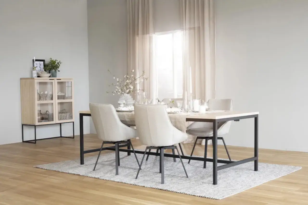 Ett ljust och luftigt rum med matbord, stolar och ett vitrinskåp i skandinavisk design.