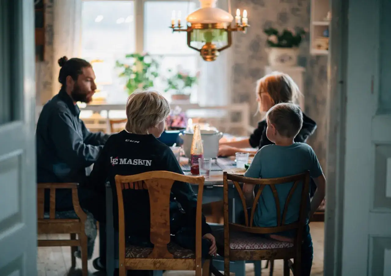 Familjen samlad runt bordet, kanske diskuterar de djupa frågor under middagen. En pappa med hästsvans, två pojkar och en kvinna.
